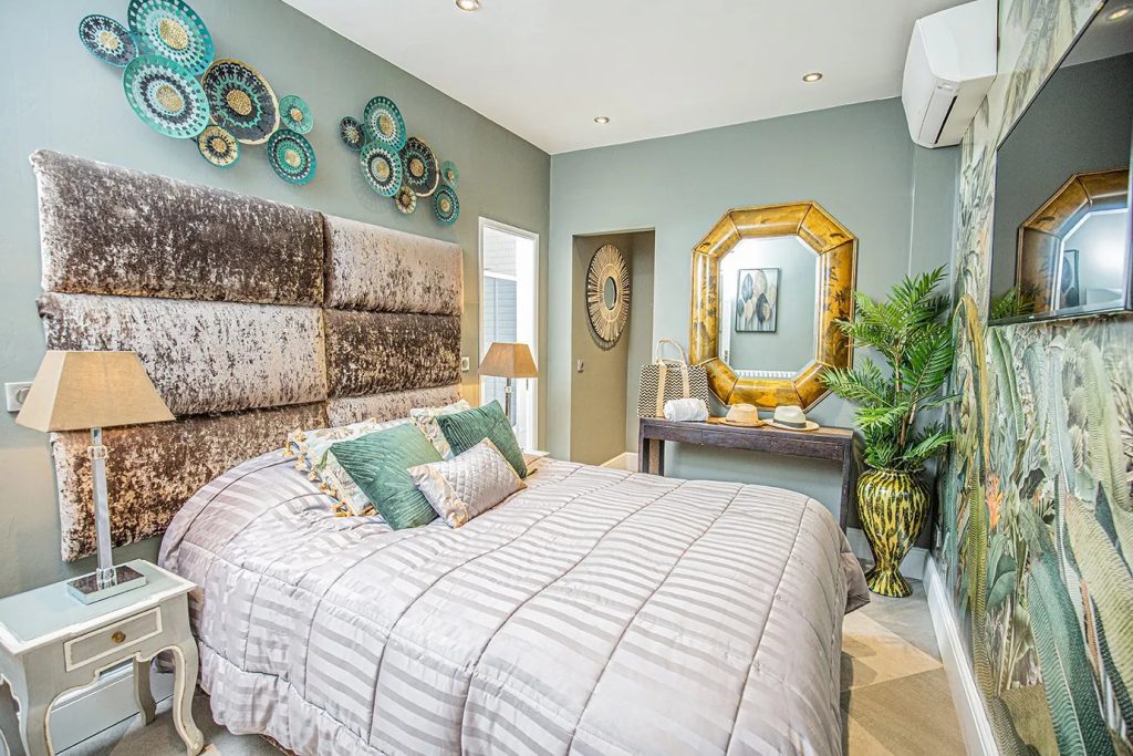 A luxurious double bedroom at  Villa Sandra, decorated with gold, aqua, and turquoise linens and furniture
