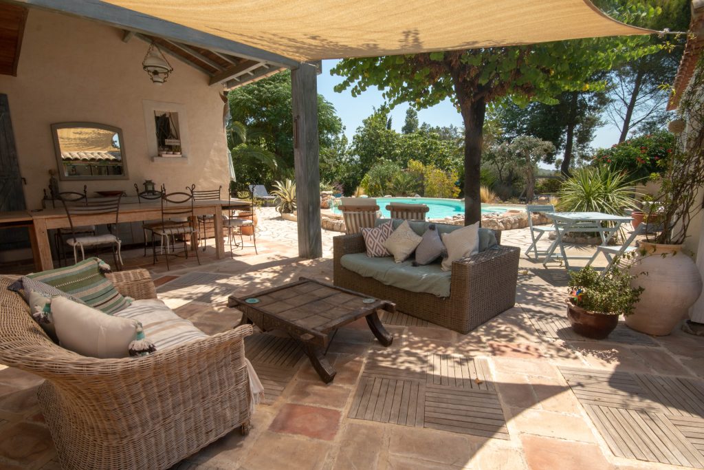 A seating and dining area in the shaded  terrace of a modern Mediterranean holiday home in a quiet village in rural France