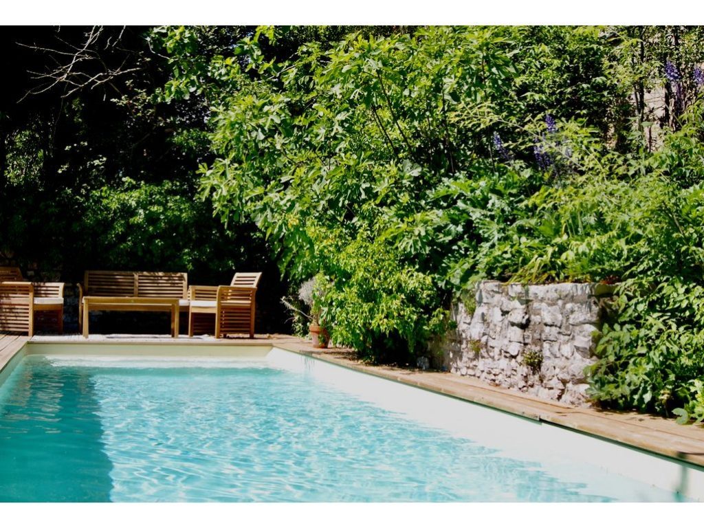 View of the saltwater pool in with wooden chairs in a private walled garden in the South of France